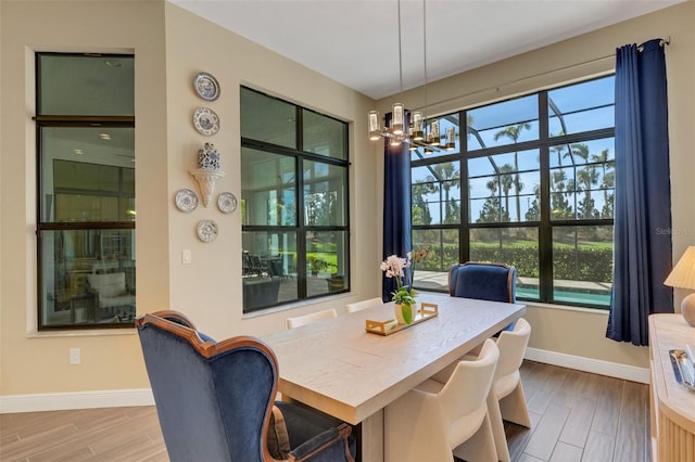 dining area featuring baseboards, wood finished floors, and a notable chandelier