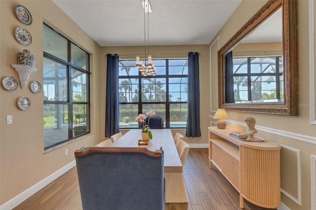 dining area featuring an inviting chandelier, baseboards, and wood finished floors