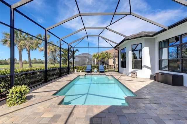 outdoor pool featuring glass enclosure and a patio