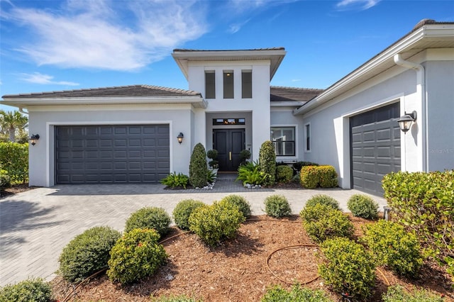 view of front facade featuring an attached garage, decorative driveway, and stucco siding