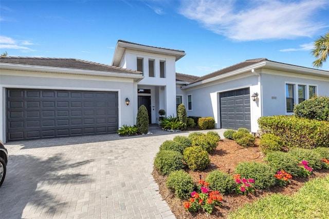 prairie-style home with decorative driveway, an attached garage, and stucco siding