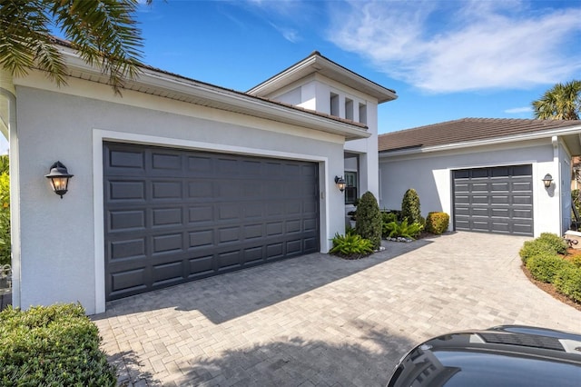 view of front of home with an attached garage, decorative driveway, and stucco siding