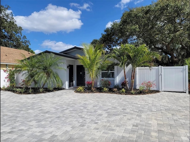 view of front of home with fence, a gate, and stucco siding