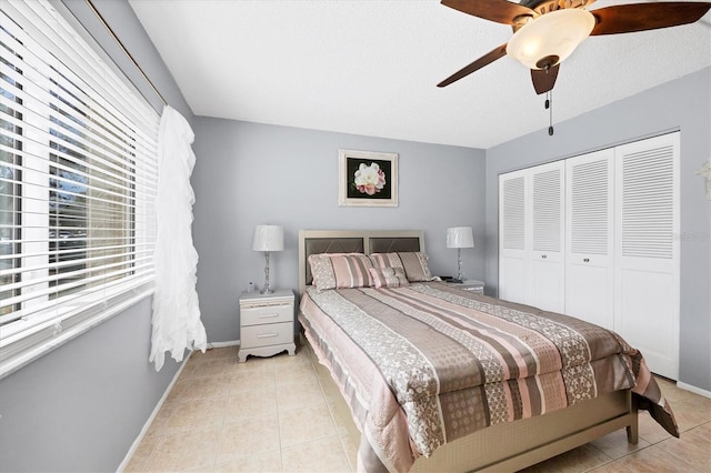 bedroom featuring light tile patterned flooring, ceiling fan, and a closet