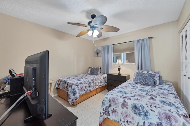 bedroom featuring light tile patterned flooring, ceiling fan, a textured ceiling, and a closet