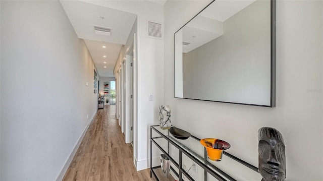 corridor featuring light wood-type flooring, baseboards, visible vents, and recessed lighting