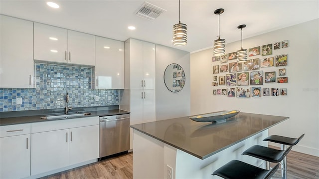 kitchen featuring dark countertops, white cabinetry, dishwasher, and visible vents