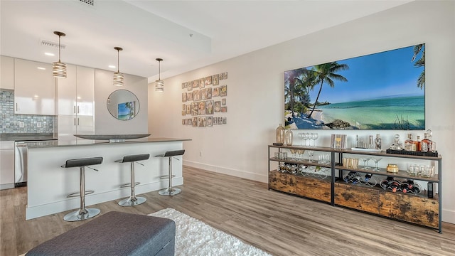 kitchen featuring a breakfast bar, visible vents, hanging light fixtures, decorative backsplash, and white cabinets