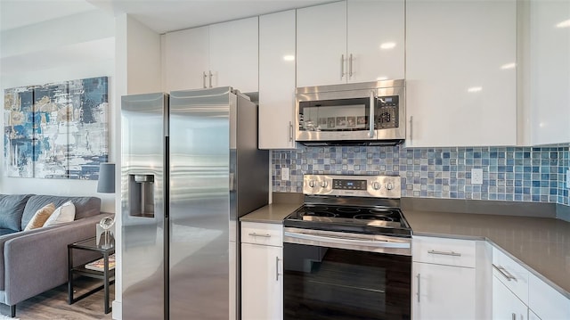 kitchen with appliances with stainless steel finishes, backsplash, and white cabinets