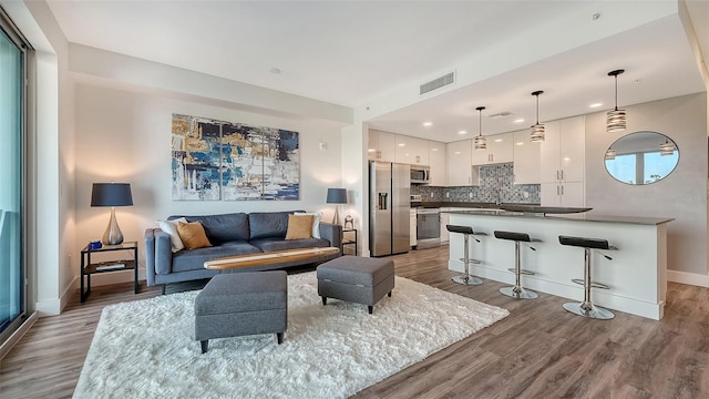 living room with recessed lighting, wood finished floors, visible vents, and baseboards