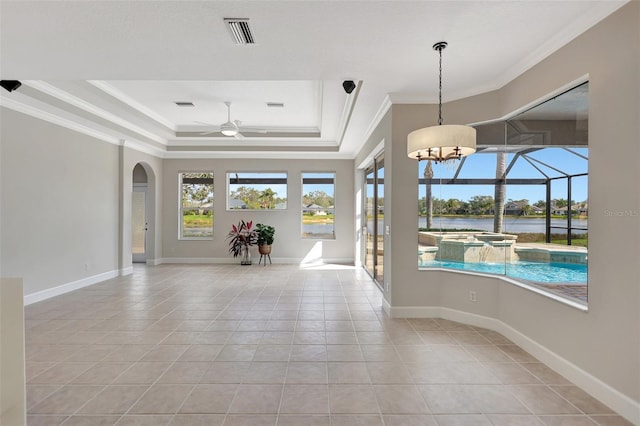 empty room with ornamental molding, light tile patterned floors, ceiling fan, a tray ceiling, and a water view