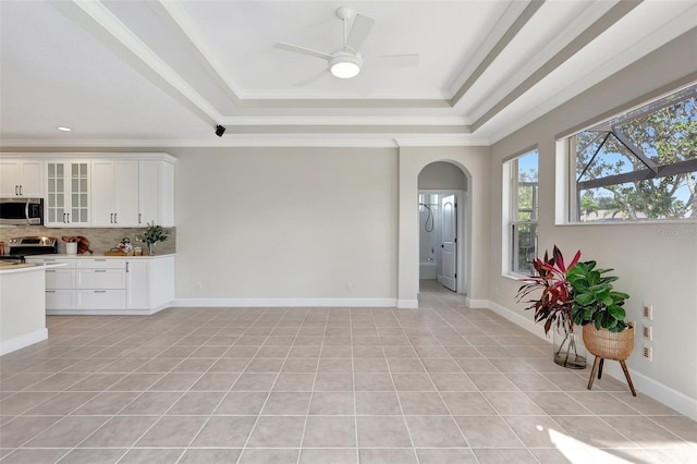 interior space featuring ornamental molding, appliances with stainless steel finishes, a raised ceiling, decorative backsplash, and white cabinets