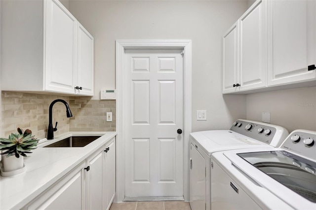 washroom featuring sink, light tile patterned floors, washing machine and dryer, and cabinets