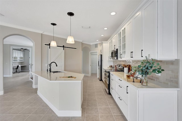 kitchen featuring sink, decorative light fixtures, appliances with stainless steel finishes, a barn door, and white cabinets