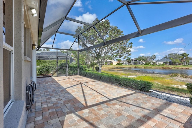 view of patio with glass enclosure and a water view