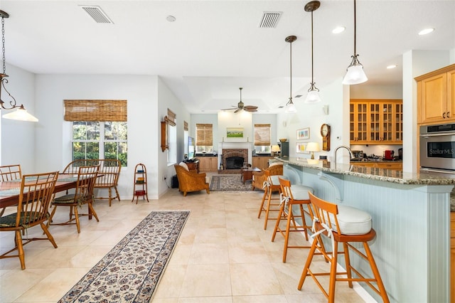 kitchen with a breakfast bar, stainless steel oven, kitchen peninsula, stone counters, and pendant lighting