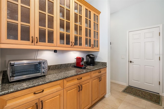 kitchen featuring light tile patterned floors and dark stone counters