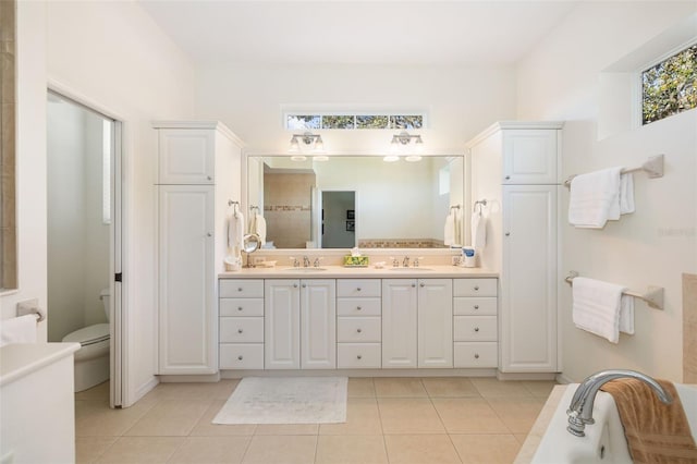 bathroom with tile patterned floors, vanity, toilet, and a tub