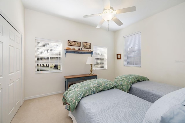 carpeted bedroom with ceiling fan and a closet