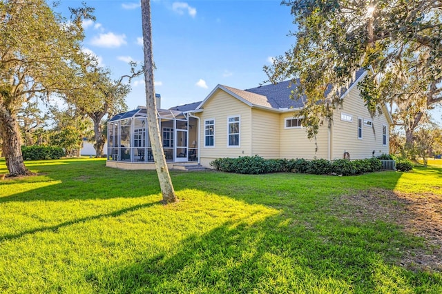 rear view of house with a lanai and a lawn