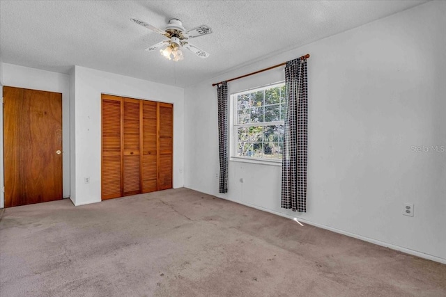 unfurnished bedroom with a textured ceiling, a closet, carpet flooring, and a ceiling fan