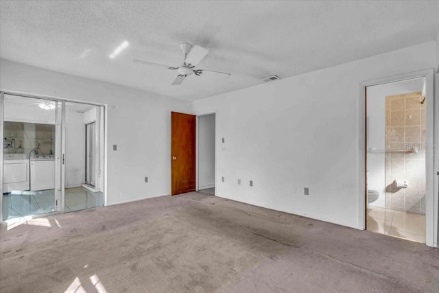 unfurnished bedroom with carpet floors, visible vents, a textured ceiling, ensuite bath, and separate washer and dryer