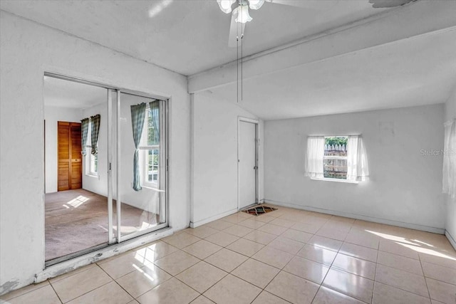 tiled spare room featuring lofted ceiling with beams and baseboards