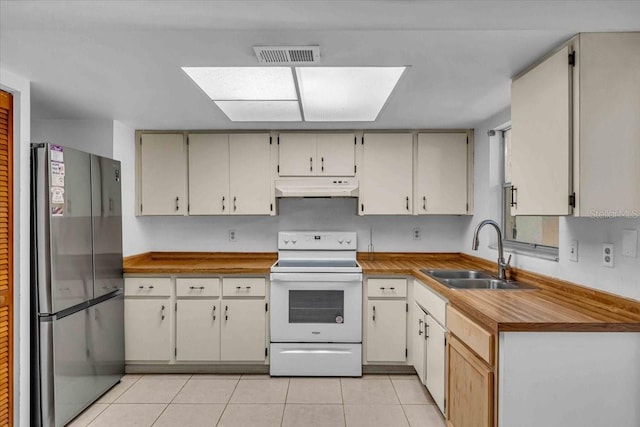 kitchen with white electric stove, visible vents, freestanding refrigerator, under cabinet range hood, and a sink