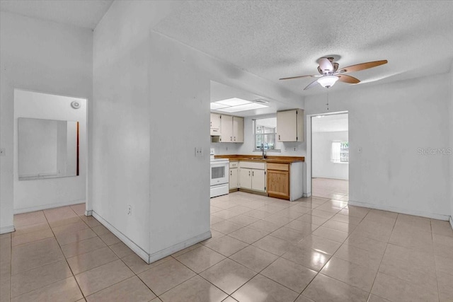 kitchen with light tile patterned floors, a textured ceiling, a ceiling fan, light countertops, and white electric range oven