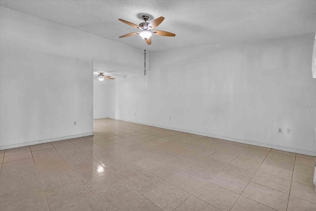 empty room featuring baseboards, ceiling fan, tile patterned floors, vaulted ceiling, and a textured ceiling