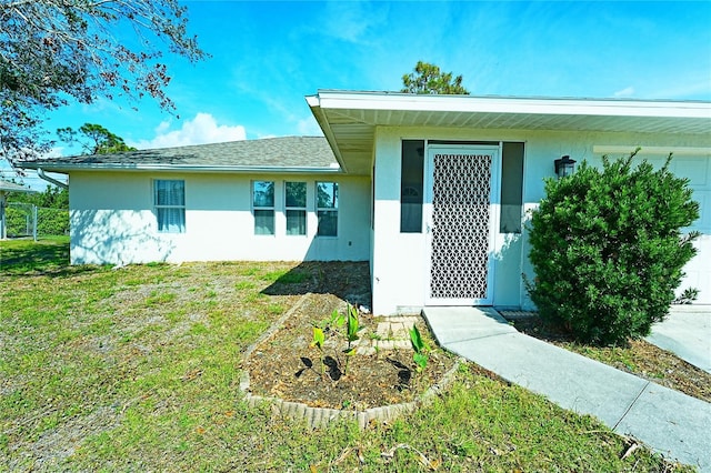 property entrance with a lawn, an attached garage, and stucco siding