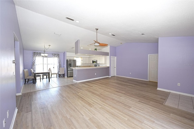 unfurnished living room featuring light wood-type flooring, baseboards, visible vents, and lofted ceiling