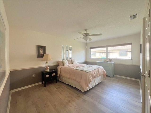 bedroom with ceiling fan, light hardwood / wood-style flooring, and a textured ceiling