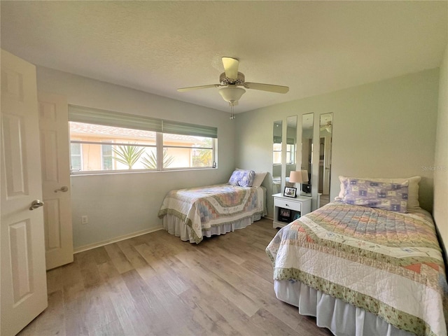 bedroom with a textured ceiling, ceiling fan, and light wood-type flooring