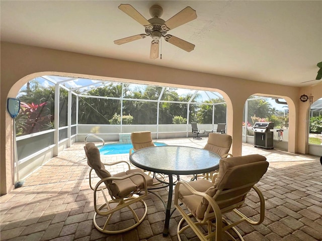 view of patio featuring ceiling fan, grilling area, and a lanai