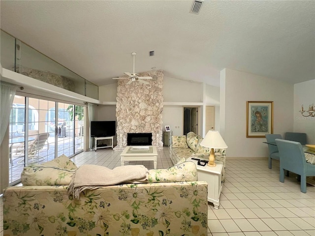 living room featuring vaulted ceiling, a stone fireplace, and ceiling fan