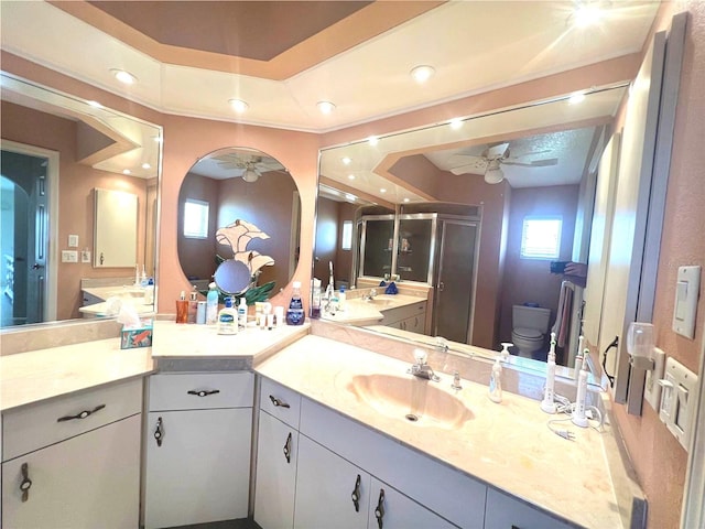 bathroom featuring vanity, an enclosed shower, ceiling fan, a tray ceiling, and toilet