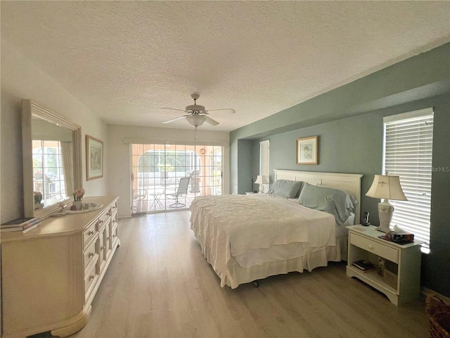 bedroom with a textured ceiling, light wood-style flooring, access to exterior, and ceiling fan