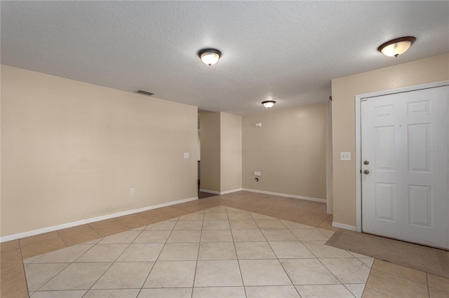 interior space featuring light tile patterned floors, visible vents, and a textured ceiling