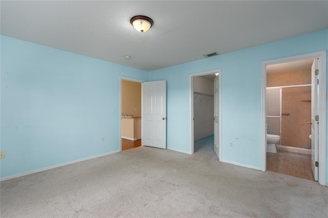 unfurnished bedroom featuring light colored carpet, visible vents, baseboards, a spacious closet, and a closet