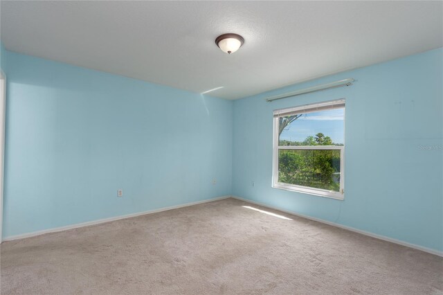 unfurnished room with light colored carpet and baseboards