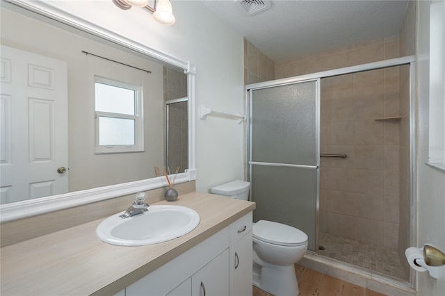 full bathroom with visible vents, toilet, a stall shower, vanity, and wood finished floors