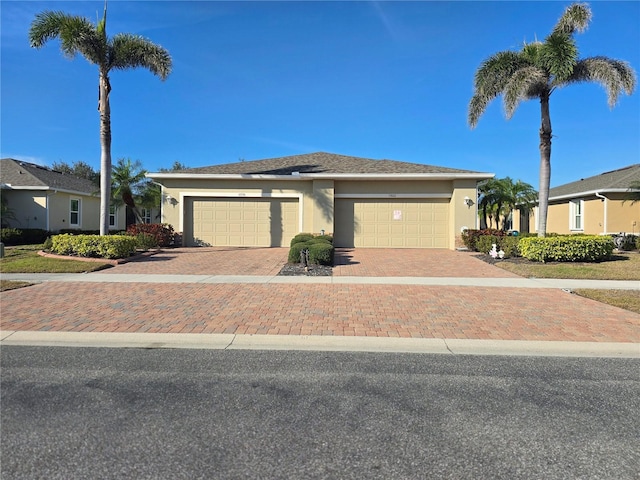 view of front of house with decorative driveway, an attached garage, and stucco siding