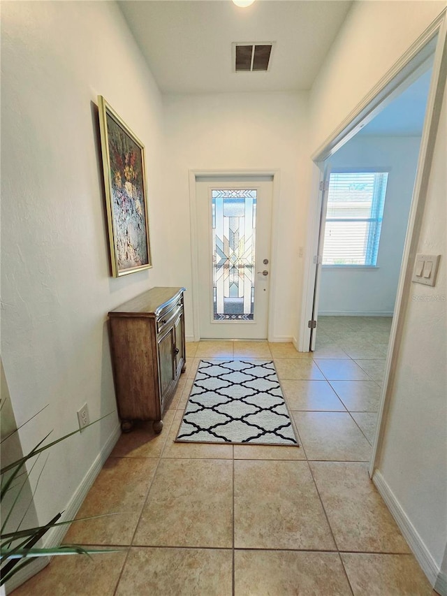 doorway to outside with light tile patterned floors, baseboards, and visible vents