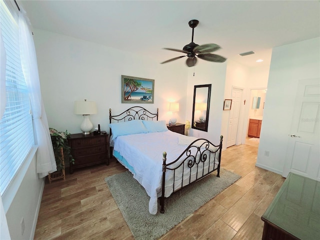 bedroom featuring ceiling fan, connected bathroom, visible vents, and light wood-style floors