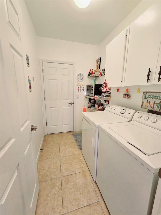 washroom with light tile patterned floors, washing machine and clothes dryer, and cabinet space