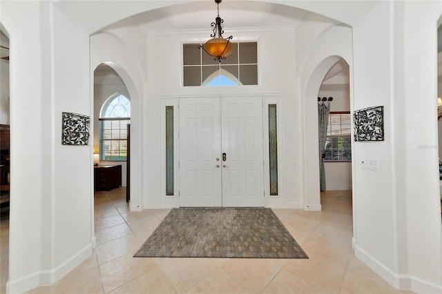 entrance foyer with crown molding and light tile patterned floors