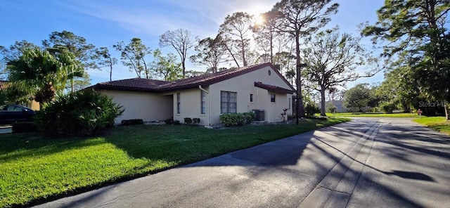 view of property exterior with a lawn and central air condition unit