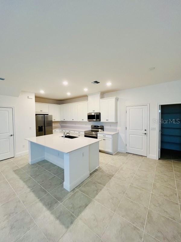 kitchen featuring white cabinetry, sink, a kitchen island with sink, light tile patterned floors, and stainless steel appliances