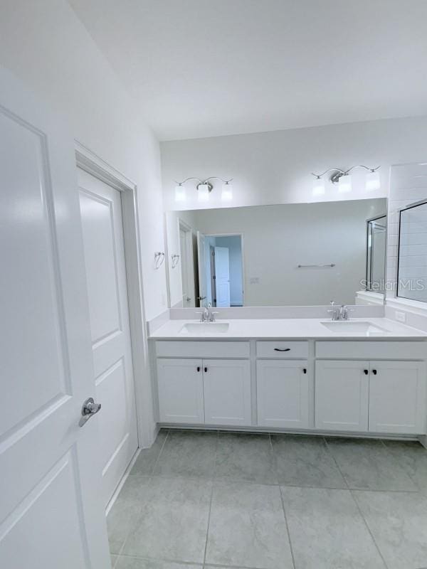bathroom featuring a sink, walk in shower, double vanity, and tile patterned flooring